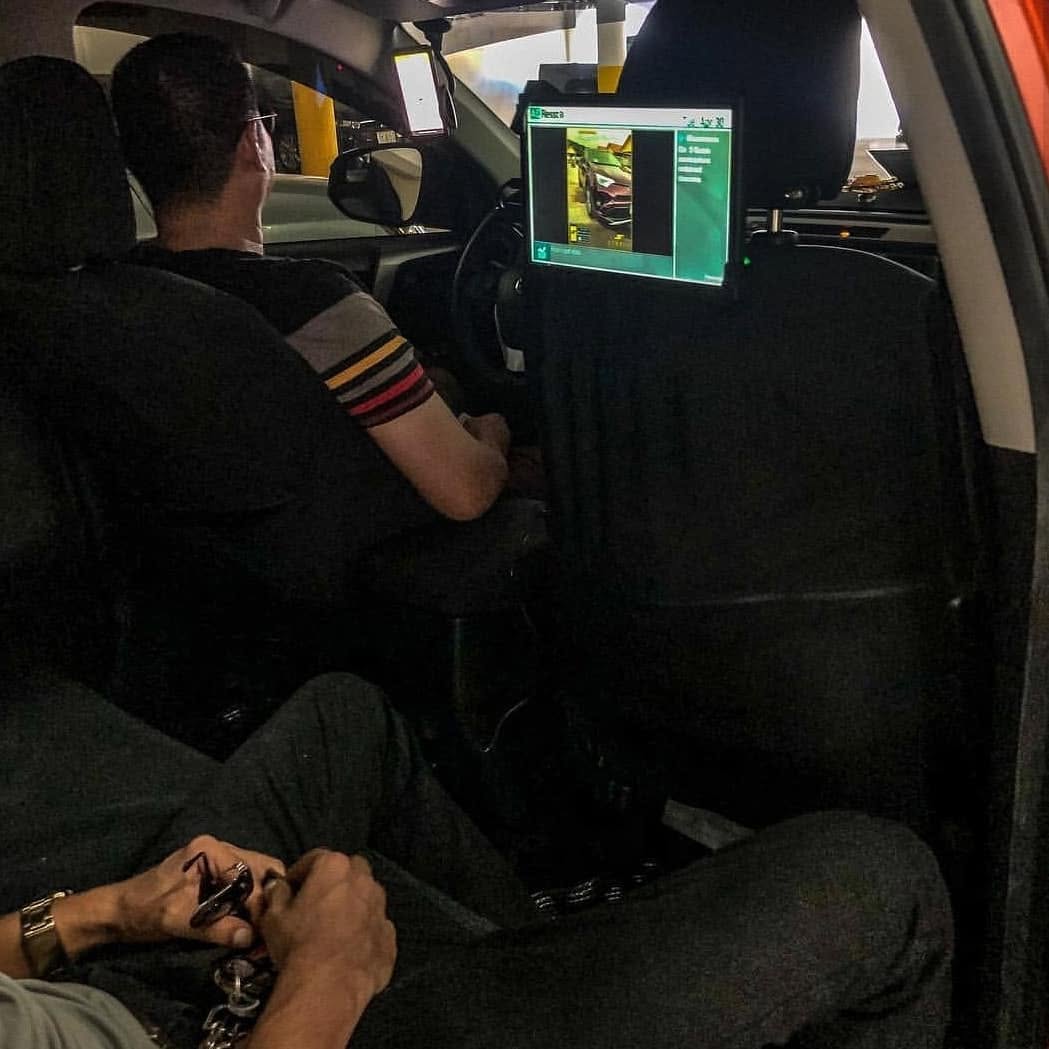 Rideshare passenger point of view of an AdResst headrest display playing an automotive ad at night